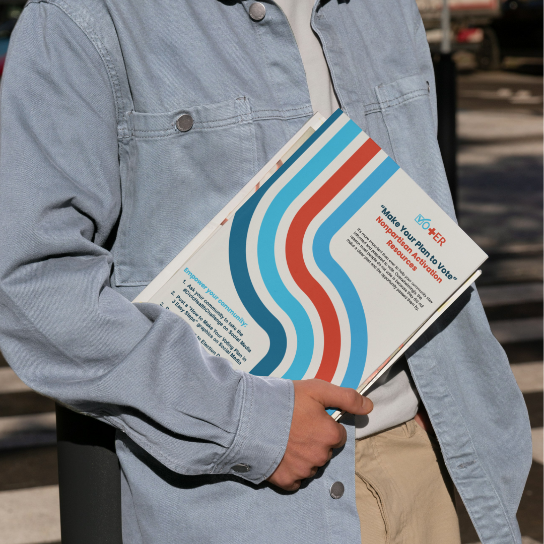 Person holding the Make Your Plan to Vote Guide on top of a stack of papers